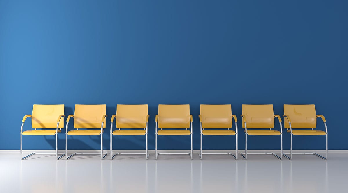 Eine Reihe gelber Stühle in einem Raum einer Klinik – Symbolbild für Klinikmarketing